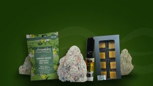Cannabis flower, a Cannapy vape cartridge, and edibles from ForeverGreen arranged on a dark green background